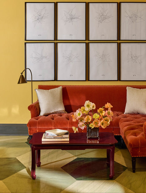 Living room with orange sofa, lacquer chinoiserie coffee table, and wall art
