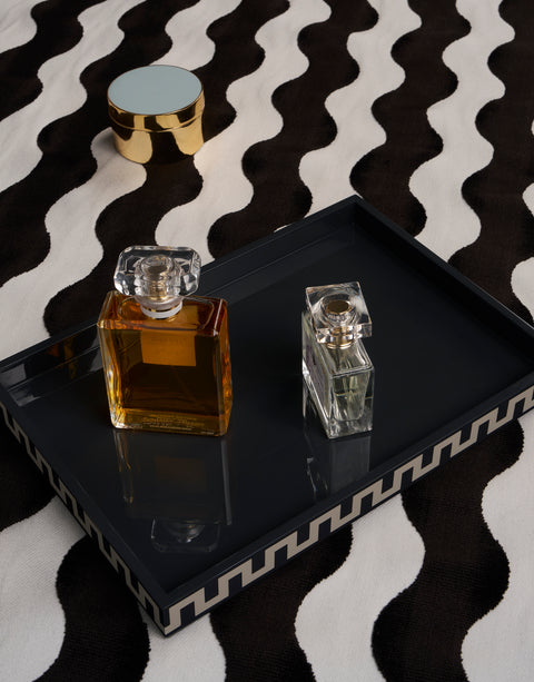 Two perfume bottles on a black and white lacquer tray with a black and white patterned background
