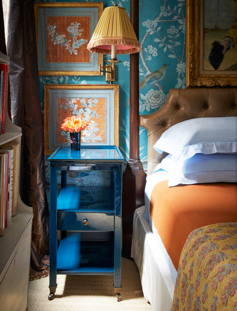 Decorative bedroom with a bed, lacquer nightstand, and wall art.